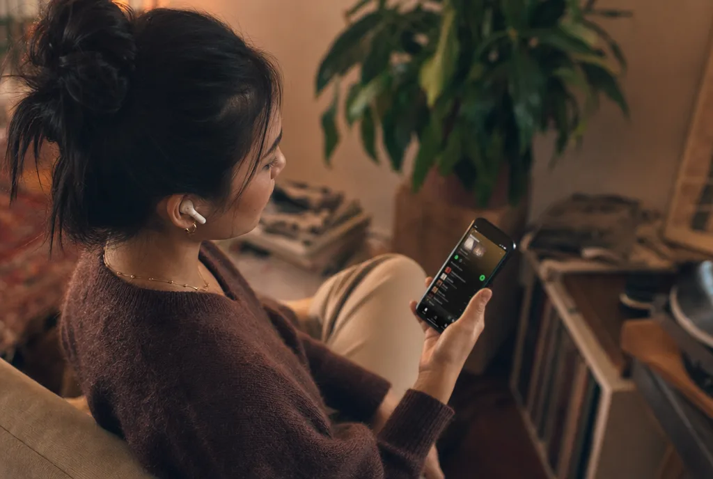 Person with earbuds listening to music on their smartphone