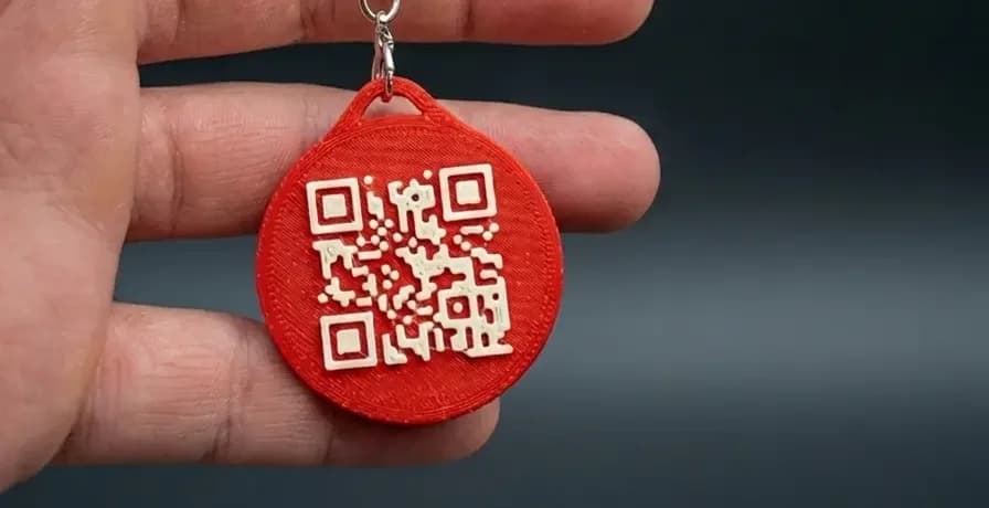 Red Tapora keychain with its printed QR code, held in a hand
